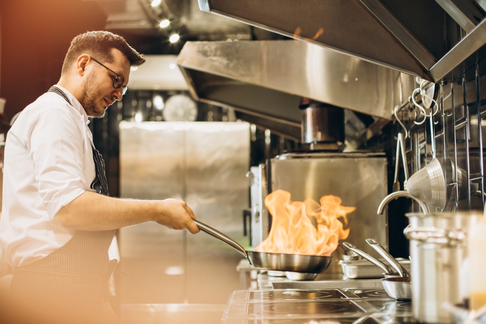 Man,Chef,Frying,Meat,In,A,Pan,In,Fire